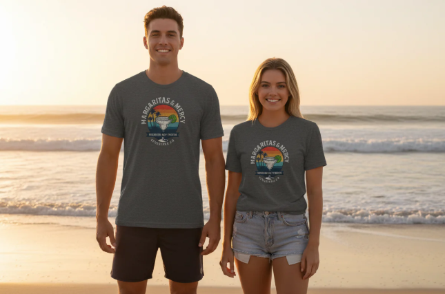 Two people wearing gray t-shirts with a logo on a beach at sunset.